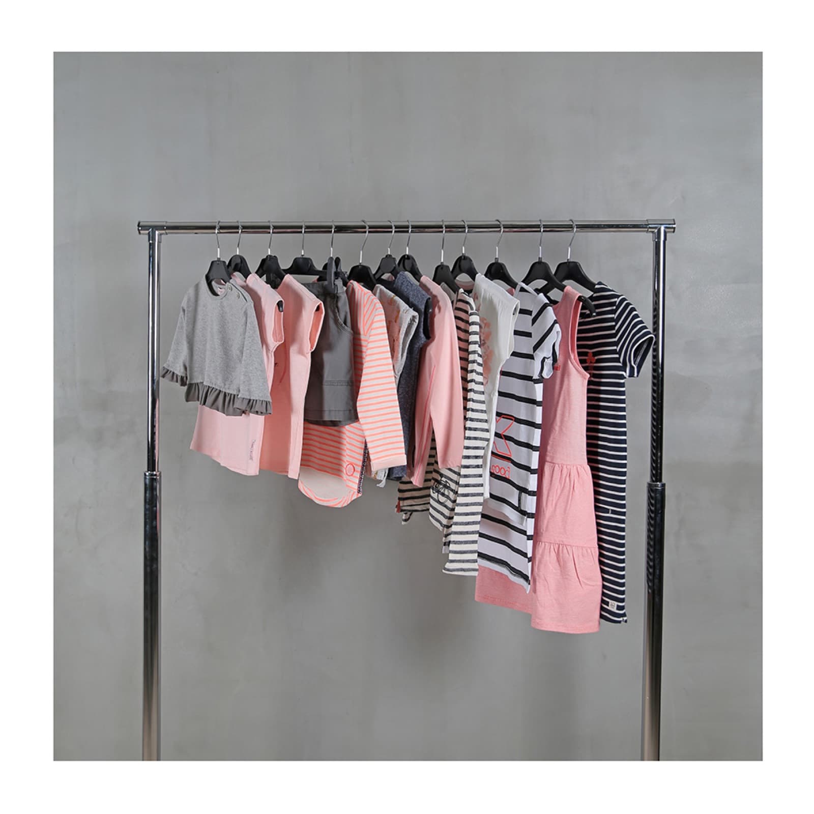 Childrenswear collection on a rail in soft pinks, greys and stripes