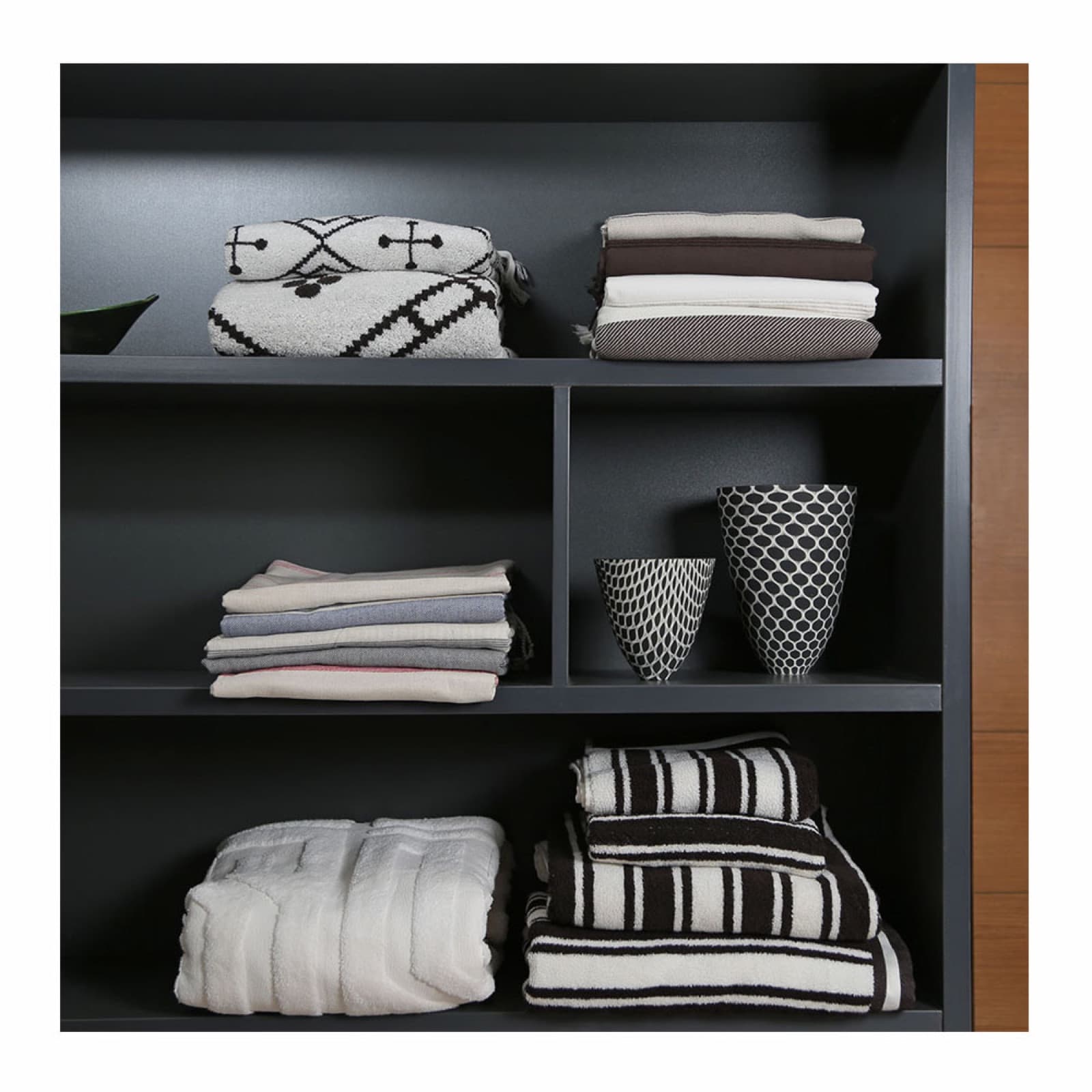 Folded towels and home textiles arranged on dark shelving