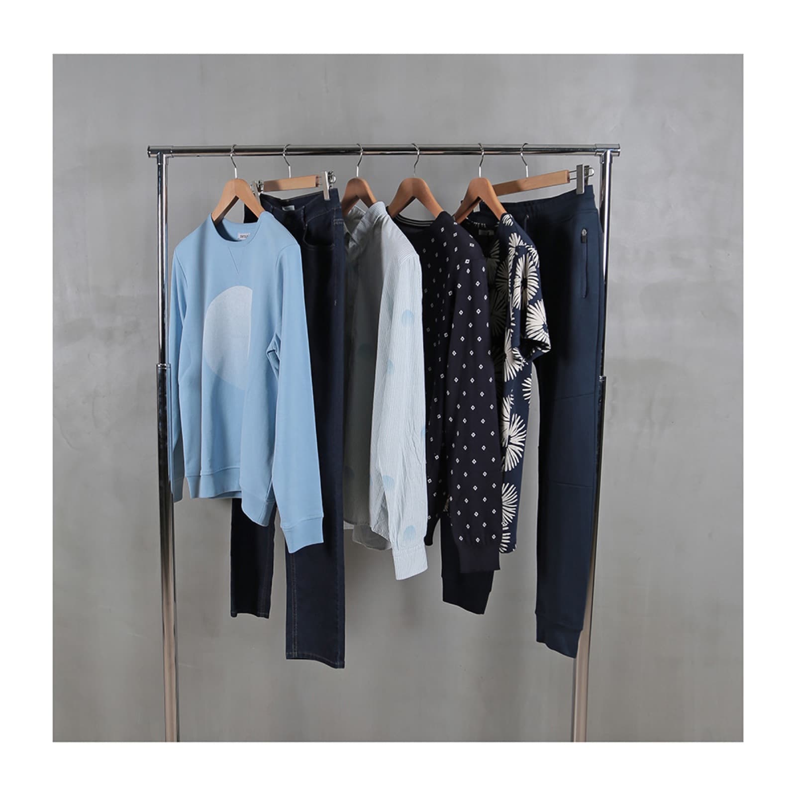 Menswear collection on a rail: sweatshirt, denim, shirts and printed tees