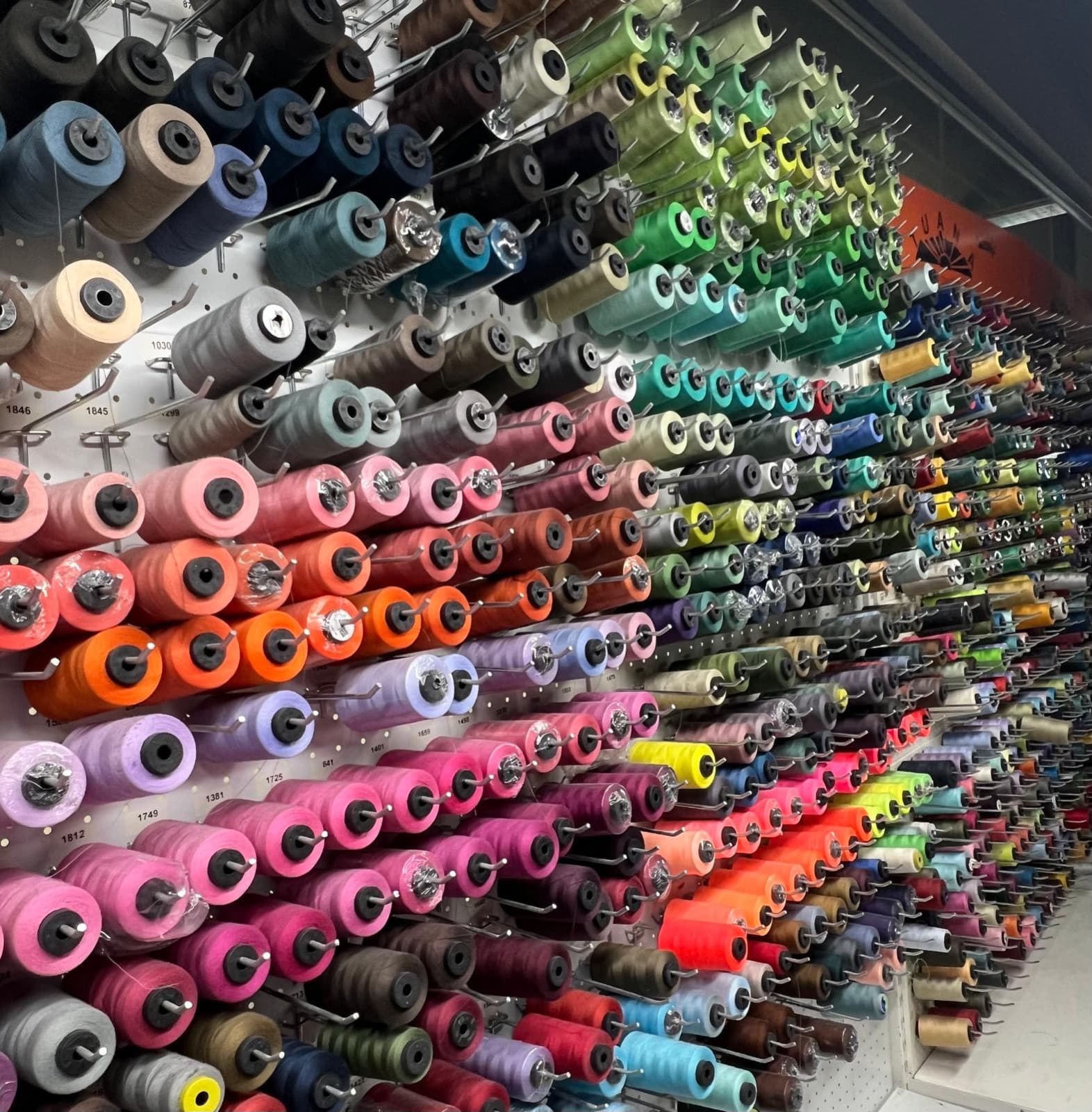 A wall of thread spools in every colour, in the workshop
